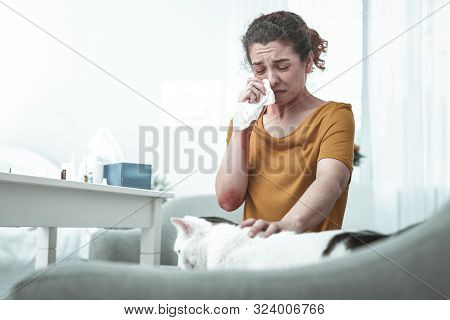 Wife Sitting On Sofa Having Strong Allergy To Cats And Dust