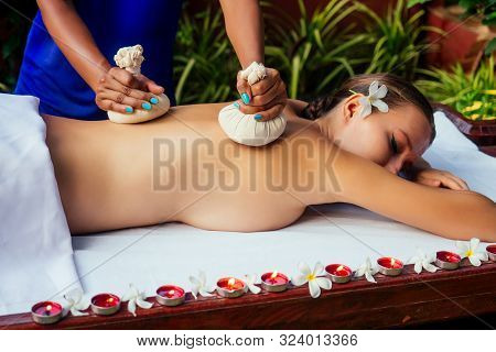 Portrait Of Young Beautiful Woman Lying On A Wooden Table In Spa Environment Flowers And Candles