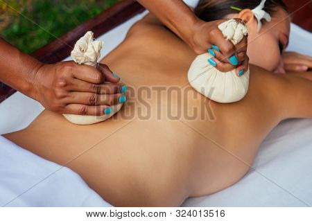 Portrait Of Young Beautiful Woman Lying On A Wooden Table In Spa Environment Flowers And Candles