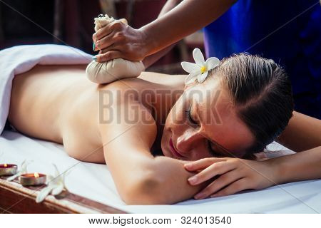 Portrait Of Young Beautiful Woman Lying On A Wooden Table In Spa Environment Flowers And Candles