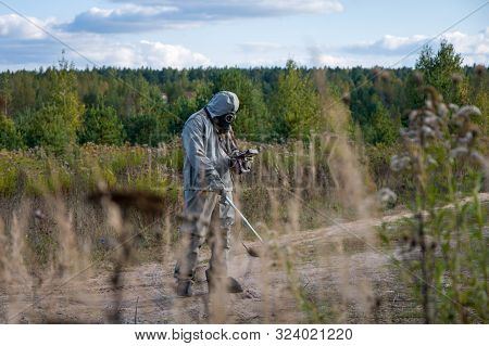 Military Dosimetrist Measures The Radiation Of The Surrounding Nature, Chemical Protective Suit And 