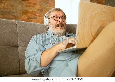 Senior Man Working With Laptop At Home - Concept Of Home Studying. Caucasian Male Model Sitting On S