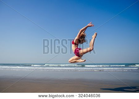 Gymnast Girl Doing Splits Grand Jete In The Air. Beautiful Young Fit Gymnast Woman Working Out, Perf