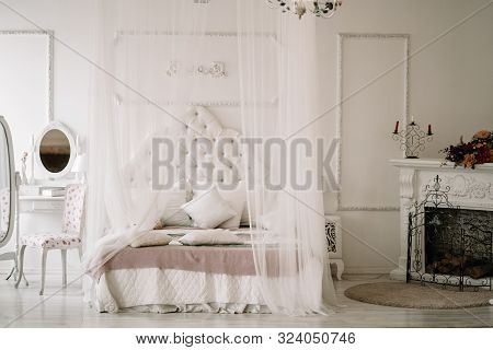 White Bedroom Interior With Nobody. Large Cozy Bed With A White Canopy And Oval Dressing Mirror With