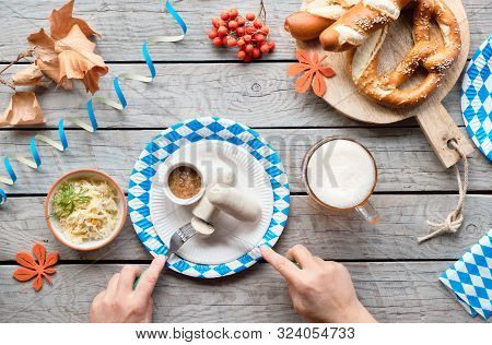 Oktoberfest Traditional Food And Beer. Hands Of The Woman Eating White Sausage. Sauerkraut And Pretz