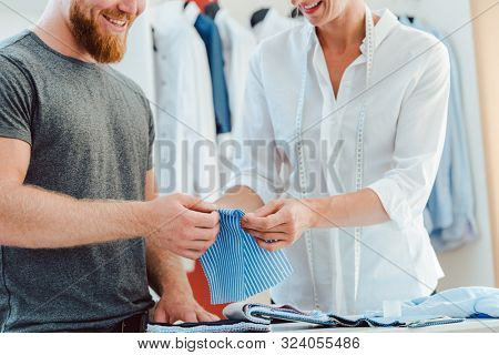 Tailor and customer choosing material for bespoke shirt from pattern book