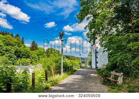 Wooden Bench, A Walking Path Next To A Chapel Between Trees And Green Vegetation, Wonderful Sunny Sp