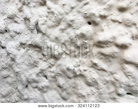 Uneven Concrete Wall Covered With White Paint.