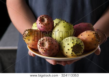 Female Hands Hold A Plate With Ripe Fresh Fruits Of Prickly Pear On A Gray Background, Low Key, Sele