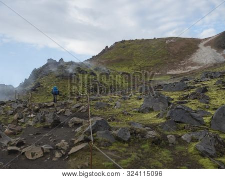 Hiker With Blue Backpack On Laugavegur Trek In Colorful Rhyolit Rainbow Mountain With Multicolored V