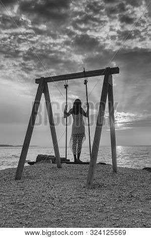 Peroj, Croatia - August 30, 2019: Unidentified Girl Standing And Resting On A Swing Near The Sea At 
