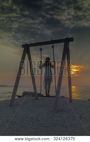 Peroj, Croatia - August 30, 2019: Unidentified Girl Standing And Resting On A Swing Near The Sea At 