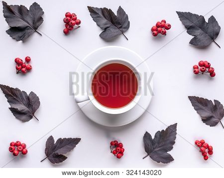Leaves And Berries Top View. Autumn Composition. Red Foliage, Ceramic Teacup And Small Fruits On Whi