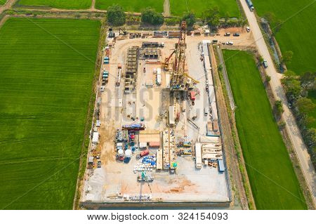 Oil And Gas Land Drilling Rig Onshore In The Middle Of A Rice Field Aerial View From A Drone