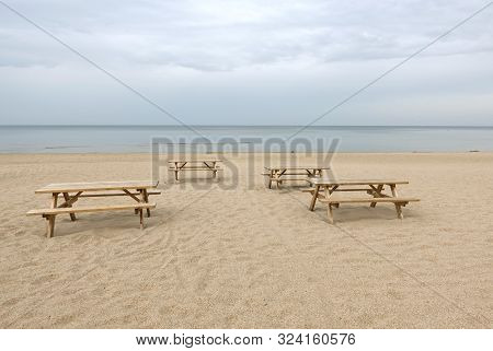 Several Wooden Tables And Benches On Empty Sandy Beach In Jurmala At The End Of Summer Season Photo 
