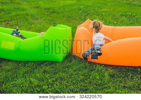 Two Cute Boys Resting On An Air Sofa In The Park.