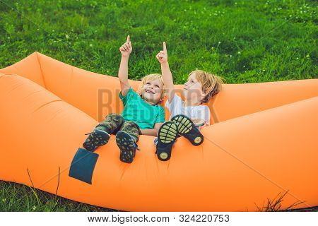 Two Cute Boys Resting On An Air Sofa In The Park.