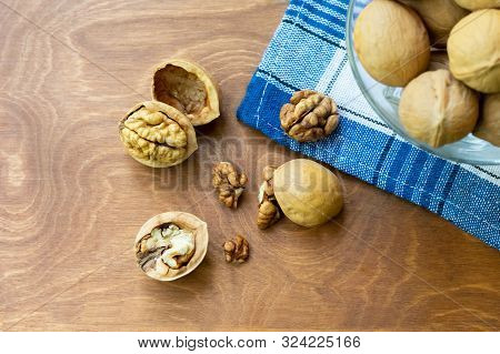 Whole Walnuts And Walnut Kernel Halves Without Shell On A Dark Wooden Table And Checkered Towel, Clo
