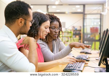 Instructor Explaining Corporate Software Specific To Trainees In Computer Class. Man And Women Sitti