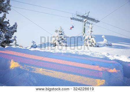 Multicoloured Reflections On The Snow And Skiing Lift Behind Them