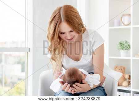 Young mother hugging cute baby at home