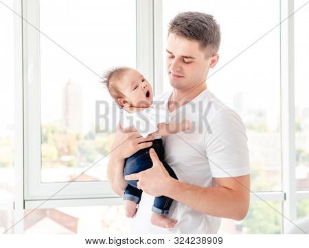 Father embracing infant near window