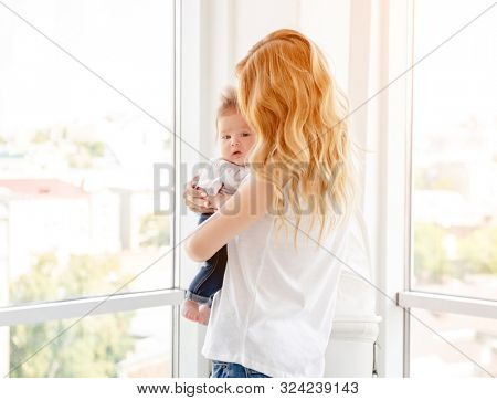 Young mother hugging cute baby at home