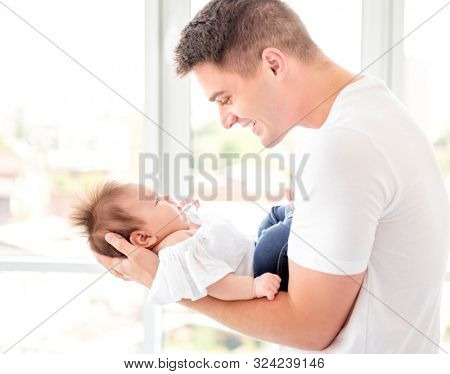 Father embracing infant near window