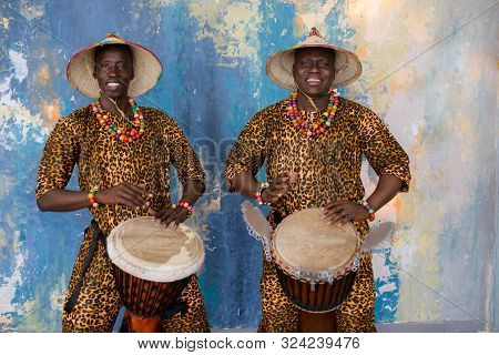 A Group Of People In Traditional African Costumes Playing Jembe Drums