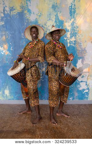A Group Of People In Traditional African Costumes Playing Jembe Drums
