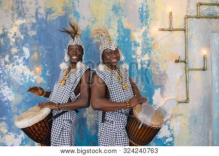 A Group Of People In Traditional African Costumes Playing Jembe Drums