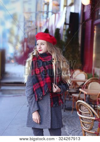 Girl With A Smile In A Gray Coat And A Red Beret With Long Curls Stands Thoughtfully Near A Cafe On 