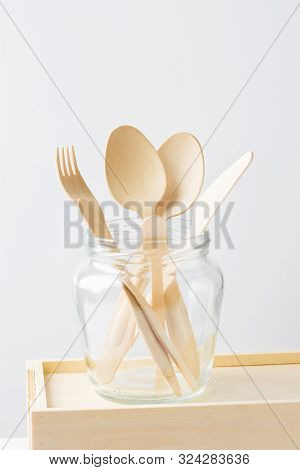 Wood Cutlery Spoons Fork Knife In A Glass Jar On White Wall Background. Zero Waste Plastic Free Reus