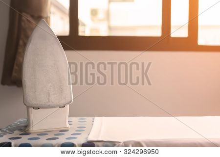 The Old Iron That Is Located On The Ironing Table With Orange Light. Old Irons Placed On The Table N