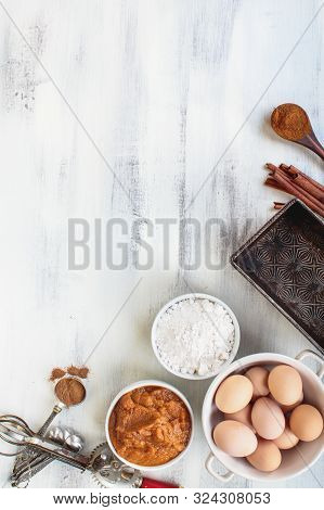 Empty Vintage Bread Loaf Pan With Pumpkin Puree, Flour, Cinnamon And Brown Eggs Over Light Rustic Ba