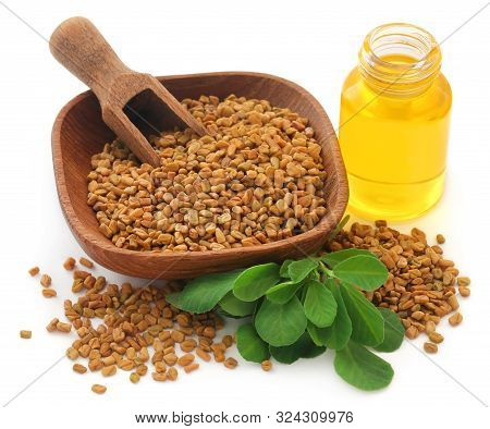 Fenugreek Seeds With Oil In Bottle Over White Background