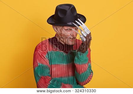 Studio Portrait Of Man In Monster Makeup, Having Long Hose And Ugly Face, Freak Hiding Behind His Ha