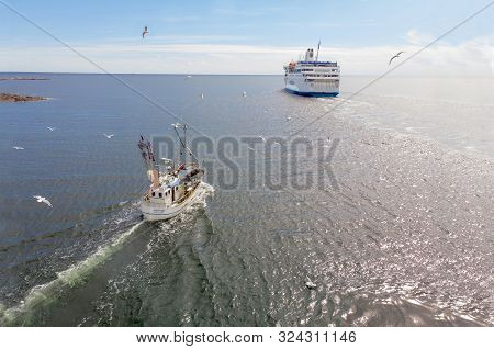 Grisslehamn, Sweden - Jul 03, 2019: Small Fishingboat, Flying Seagulls And A Passenger Ferry On The 