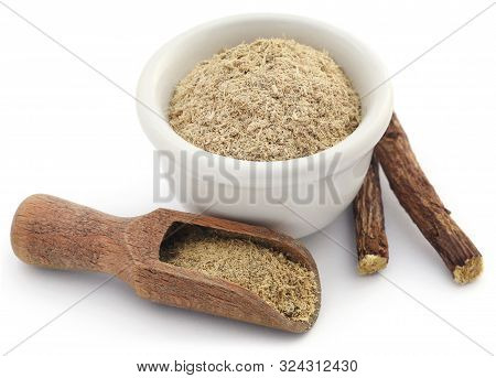 Liquorice Stick And Ground In A Small Bowl Over White Background