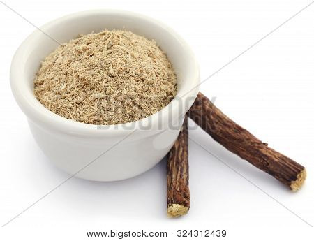 Liquorice Stick And Ground In A Small Bowl Over White Background