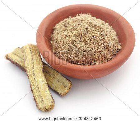 Liquorice Stick And Ground In A Small Bowl Over White Background