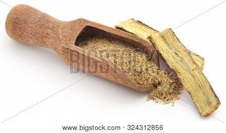 Liquorice Stick And Ground In A Wooden Scoop Over White Ackground