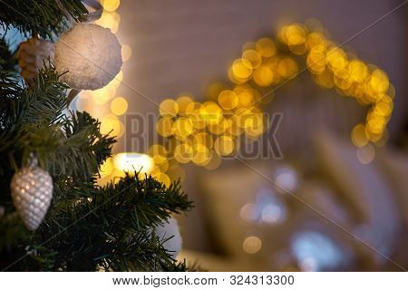 Xmas, Christmas Interior On Background Cozy Lights. A Part Of The Christmas Tree With Toys In The Be