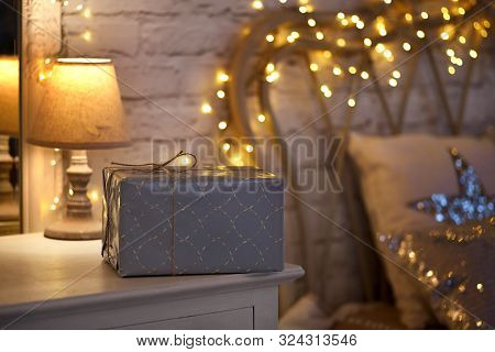Christmas In The Bedroom. Christmas Interior On A White Wall Background With Cozy Lights. Gift Box O
