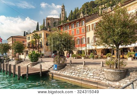 View Of Picturesque Village Morcote With Outdoor Bars And Gift Shops On The Shore Of Lake Lugano In