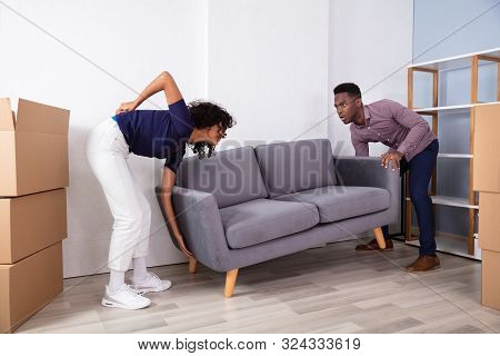 Woman Having Backpain While Lifting The Sofa At Home