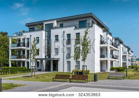 Real Estate Modern Apartments And Penthouses Surrounded By Grassy Areas Blue Sky Green Meadow Expens