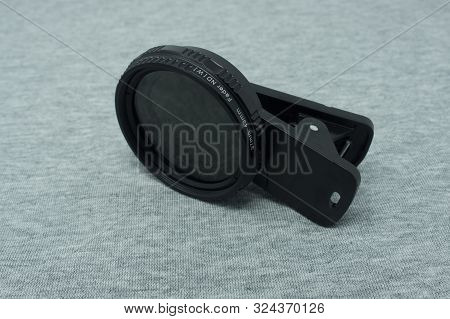 Variable Neutral Density Filter With Clip For Smartphones. Fabric, Grey Background.