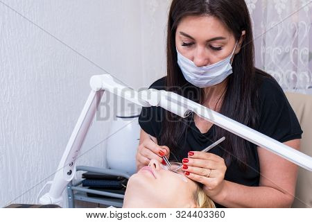 Beauty Saloon. Close-up, Procedure For Eyelash Extension. The Master Glues Each Cilium With Special 