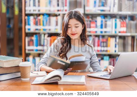 Asian Young Student In Casual Suit Doing Homework And Using Technology Laptop In Library Of Universi
